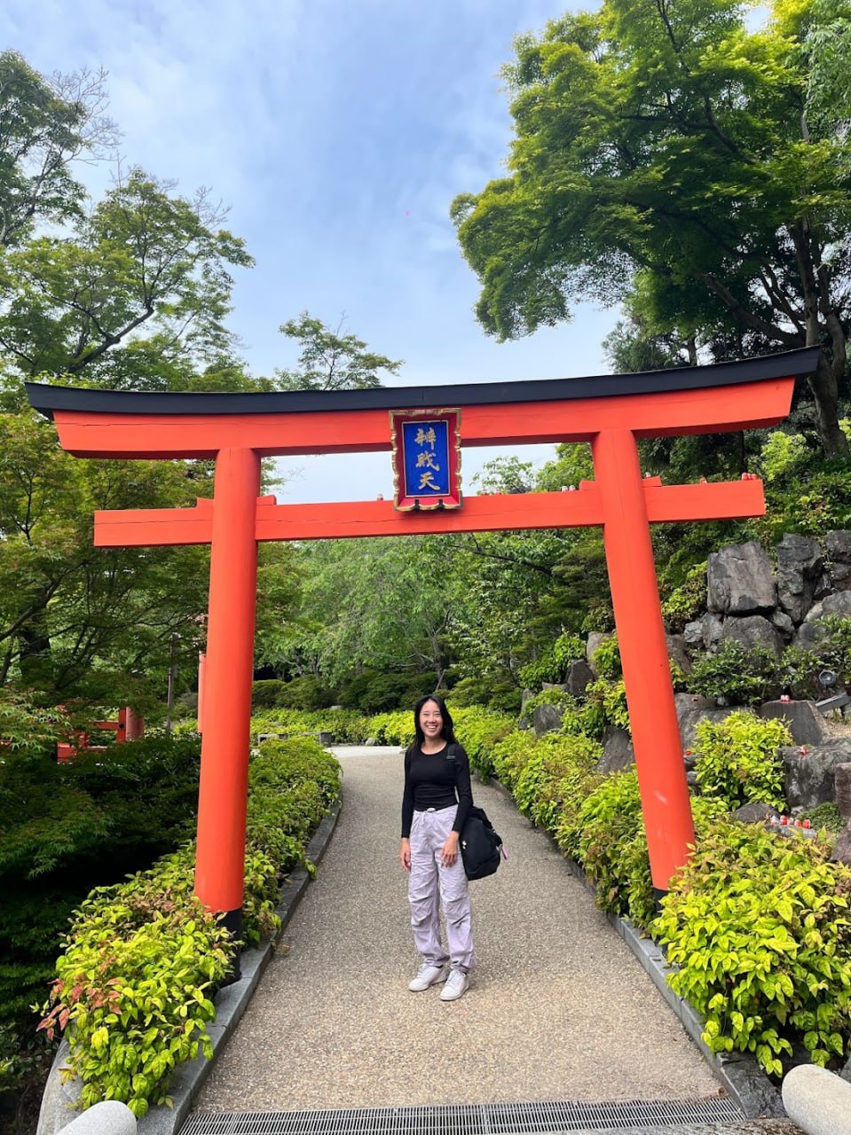 Under the red torii gate at Katsuoji Temple surrounded by lush greenery